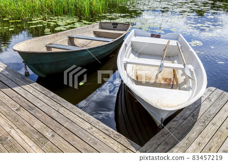 Old plastic fishing boats on the bank of the lake Old plastic fishing boats on the bank of the lake 83457219