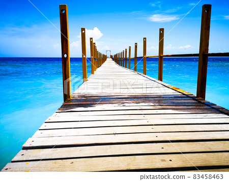 A photo of nature taken on a smartphone. Pier going into the blue sea. Beautiful boat dock in Bali. The pier goes into perspective against the background of the sea and the blue sky. A photo of nature taken on a smartphone. Pier going into the blue sea. Beautiful boat dock in Bali. The pier goes into perspective against the background of the sea and the blue sky. 83458463