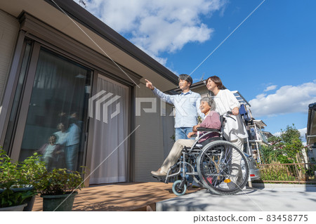 坐在輪椅上的祖母、兒子和孫子站在房子的露台上 坐在輪椅上的祖母、兒子和孫子站在房子的露台上 83458775
