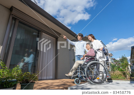 坐在輪椅上的祖母、兒子和孫子站在房子的露台上 83458776