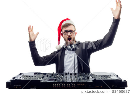 Funny screaming guy dj in Santa's hat, glasses plays music on a turntable raises hands up. studio shot  83460627