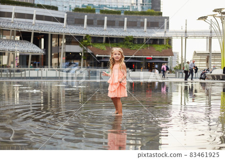 happy baby girl play with water in a fountain 83461925
