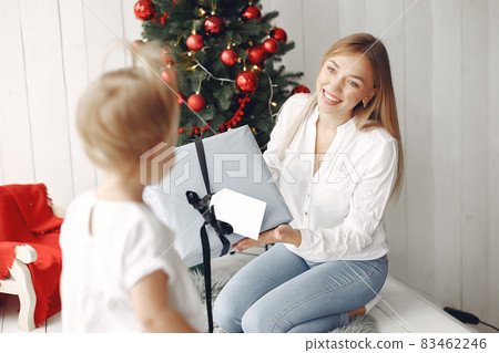 Mother with little daughter sitting near Christmas tree and gifts. Mother with little daughter sitting near Christmas tree and gifts. 83462246