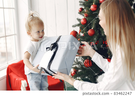 Mother with little daughter sitting near Christmas tree and gifts. Mother with little daughter sitting near Christmas tree and gifts. 83462247