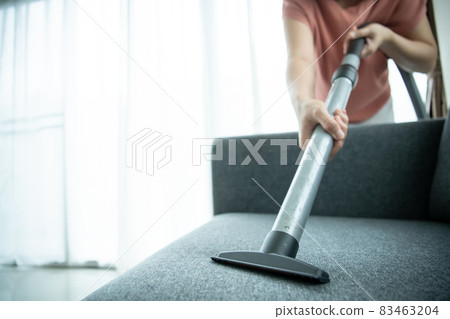 Housewife using vacuum cleaning sofa. 83463204