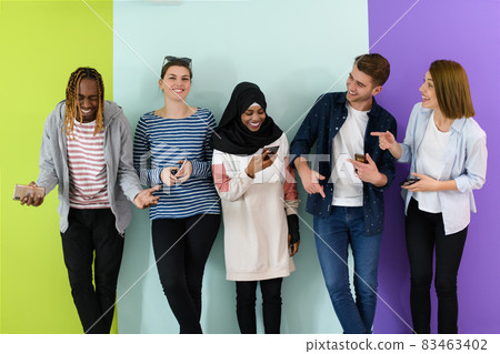diverse teenagers use mobile devices while posing for a studio photo in front of a pink background diverse teenagers use mobile devices while posing for a studio photo in front of a pink background 83463402