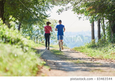 couple enjoying in a healthy lifestyle while jogging on a country road couple enjoying in a healthy lifestyle while jogging on a country road 83463544