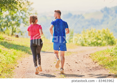 couple enjoying in a healthy lifestyle while jogging on a country road 83463962