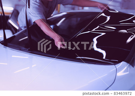 Car specialist applying tinting foil on a car window in auto service. Car specialist applying tinting foil on a car window in auto service. 83463972