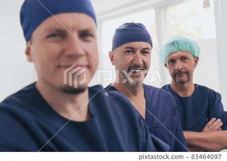 Multiethnic orthopedic doctor in front of his medical team looking at camera wearing face mask  83464097