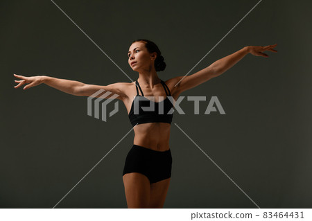 Emotional Female Ballet Dancer in Body Suit and Posing in Dance in Various Poses Against Gray Background Emotional Female Ballet Dancer in Body Suit and Posing in Dance in Various Poses Against Gray Background 83464431