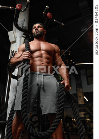 bald brutal sexy strong bodybuilder athletic fitness man pumping up abs muscles workout bodybuilding concept background 83464505