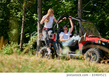 couple enjoying beautiful sunny day while driving a off road buggy 83464521