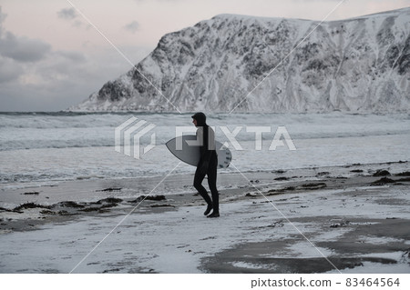 Arctic surfer going by beach after surfing 83464564