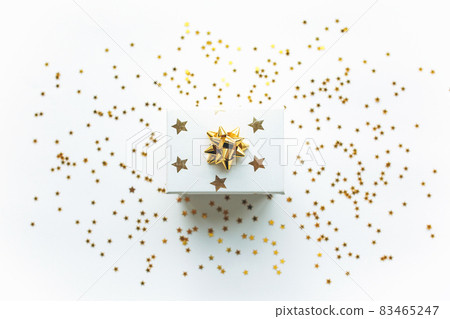 Gift white box with a gold tape with tinsel and confetti on a white background. The concept of a gift, a new year, a festive background 83465247