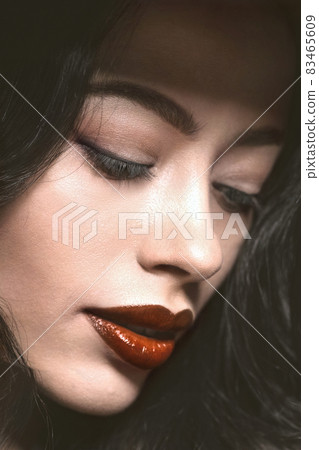 Tender young woman face with beautiful long dark hair. Young female model with professional make-up. Fashion, beauty, makeup, hairstyle, personal care, beauty salon, cosmetics. Fashion, beauty 83465609