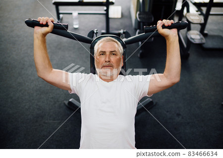 Elderly man, workout on exercise machine, gym Elderly man, workout on exercise machine, gym 83466634