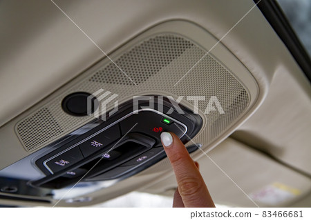 female driver's finger presses the sos button on the ceiling panel of a modern car female driver's finger presses the sos button on the ceiling panel of a modern car 83466681