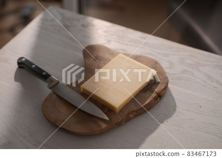 Small block of aged cheese on wood board with knife Small block of aged cheese on wood board with knife 83467173