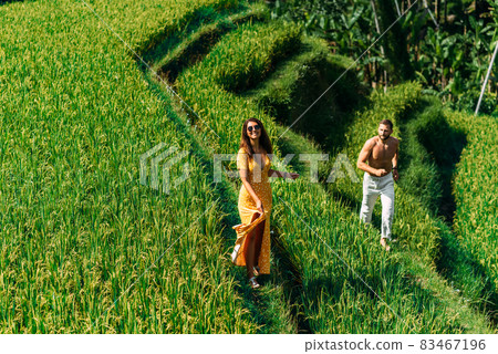 Man and woman running on rice terraces. A couple in love travels through Asia. Man and woman are traveling in Indonesia. Happy couple on the island of Bali. Rice terraces in Bali. Copy space Man and woman running on rice terraces. A couple in love travels through Asia. Man and woman are traveling in Indonesia. Happy couple on the island of Bali. Rice terraces in Bali. Copy space 83467196