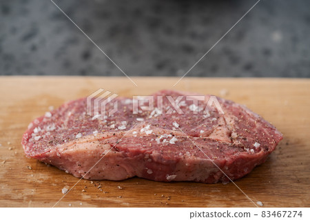 Raw ribeye steak spiced and ready to cook on oak board 83467274