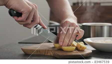 Man cutting potatoes before baking 83467539