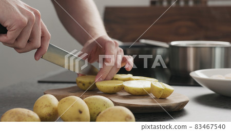 Man cutting potatoes before baking Man cutting potatoes before baking 83467540