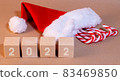2022 figures on wooden cubes santa Claus hat and candy canes Christmas background in craft style 83469850