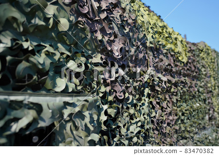 Armoured military vehicle covered with camouflage fabric mesh, closeup detail Armoured military vehicle covered with camouflage fabric mesh, closeup detail 83470382