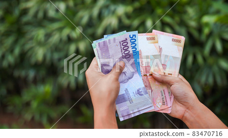 The girl recounts in the hands of Indonesian money. Indonesian rupee. 83470716