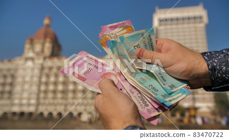 A man considers Indian rupees on the street of Mumbai. Hands close up. 83470722