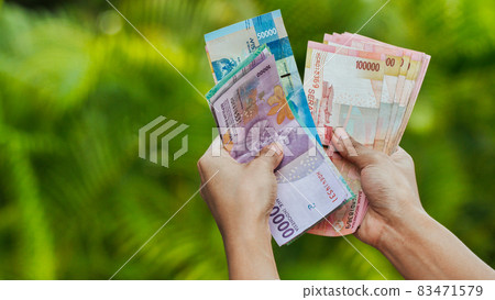 The girl recounts in the hands of Indonesian money. Indonesian rupee. The girl recounts in the hands of Indonesian money. Indonesian rupee. 83471579