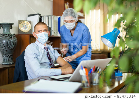 Young nurse in a protective mask, vaccinates a man Young nurse in a protective mask, vaccinates a man 83473314