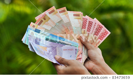 The girl is holding Indonesian money. Indonesian rupee. The girl is holding Indonesian money. Indonesian rupee. 83473659