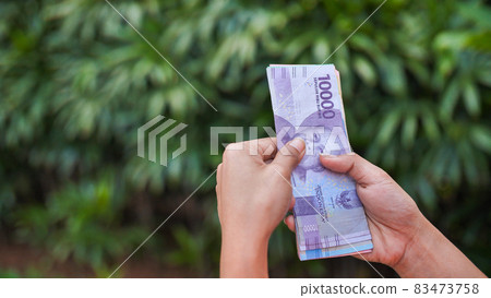 The girl recounts in the hands of Indonesian money. Indonesian rupee. The girl recounts in the hands of Indonesian money. Indonesian rupee. 83473758