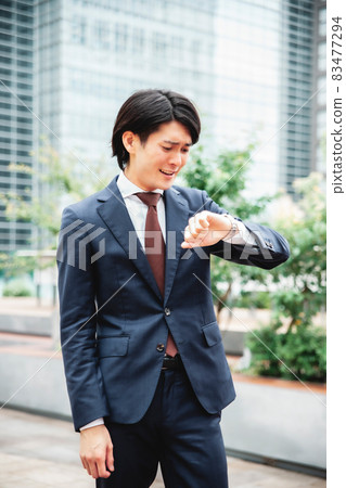 A businessman who is impatient looking at the clock (late) A businessman who is impatient looking at the clock (late) 83477294