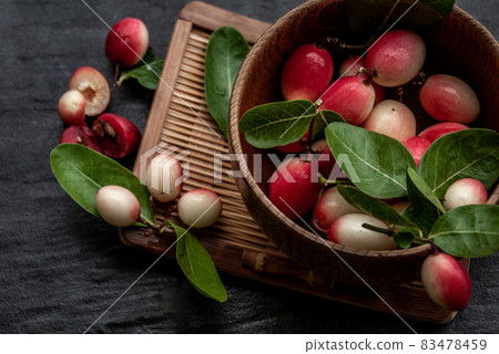 Bengal-Currants, Carandas-plum or Karonda fruit (Carissa carandas L.) sour taste fruit in Wooden cup on wicker. 83478459