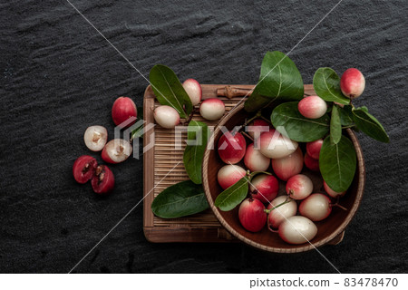 Bengal-Currants, Carandas-plum or Karonda fruit (Carissa carandas L.) sour taste fruit in Wooden cup on wicker. 83478470