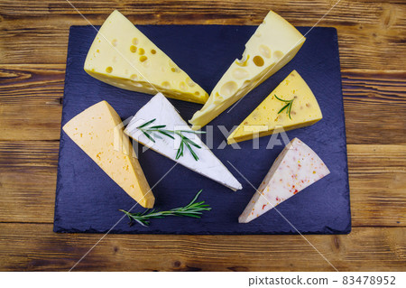 Set of various types of cheese on black slate board on a wooden table. Top view Set of various types of cheese on black slate board on a wooden table. Top view 83478952