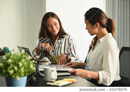 Two happy businesswomen discussing project strategy together. Two happy businesswomen discussing project strategy together. 83479079