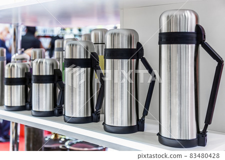 stainless metal thermos flasks are on the counter 83480428