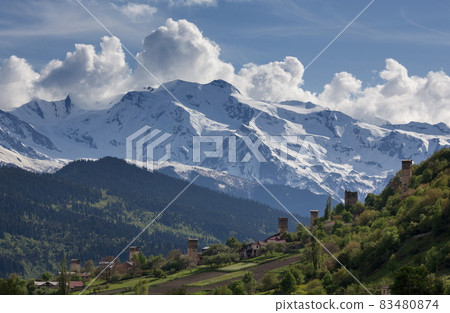 landscape, with Svan watchtowers and agricultural fields on the background of snow-capped mountain peaks clouds, Svaneti, Georgia landscape, with Svan watchtowers and agricultural fields on the background of snow-capped mountain peaks clouds, Svaneti, Georgia 83480874