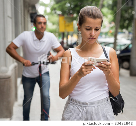 Couple using smartphones on street Couple using smartphones on street 83481948