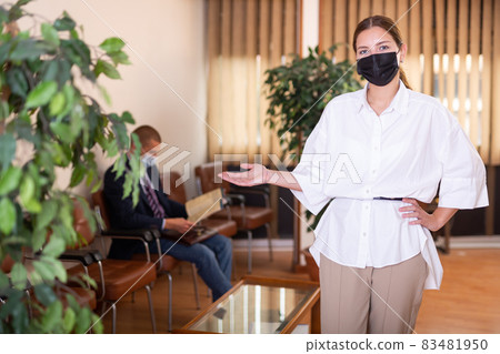 Portrait of a young confident girl in a protective mask standing in the lobby 83481950