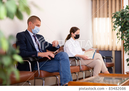 Focused young man in a protective mask, sitting in the lobby 83482086