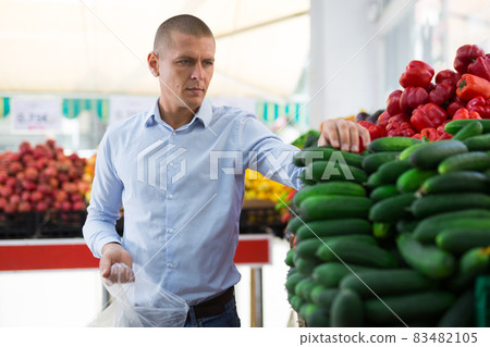 Man choosing cucumbers in supermarket Man choosing cucumbers in supermarket 83482105