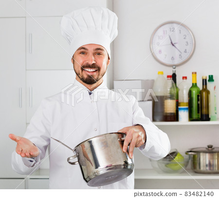 Smiling man cook making tasty dishes in kitchen Smiling man cook making tasty dishes in kitchen 83482140