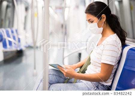 Oriental woman in mask reading book in metropolitan train 83482242
