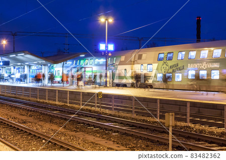 KOUVOLA, FINLAND - NOVEMBER 8, 2018: Long exposure photo. Train on the station at night. Blurred passengers with travel bags walking and staying on the platform. KOUVOLA, FINLAND - NOVEMBER 8, 2018: Long exposure photo. Train on the station at night. Blurred passengers with travel bags walking and staying on the platform. 83482362