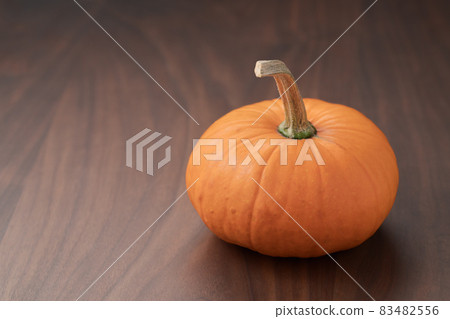 Small orange pumpkin on black walnut table with copy space 83482556